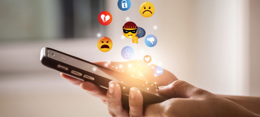Social Media Negative Emojis depicting scams floating over mobile phone