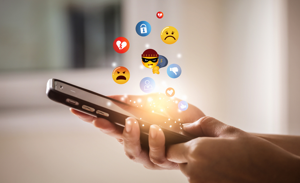 Social Media Negative Emojis depicting scams floating over mobile phone